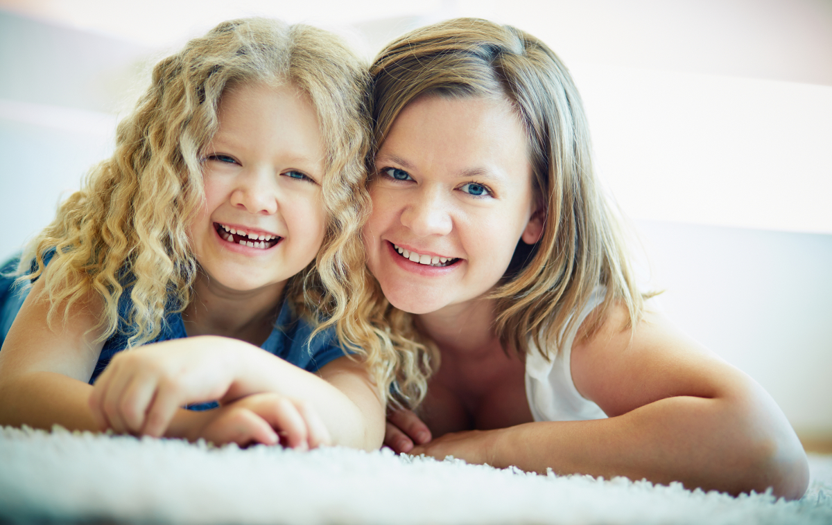 Portrait of happy woman and her daughter lying on the floor